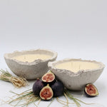 Two concrete bowls with candles and figs on a white background