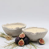 Two concrete bowls with candles and figs on a white background