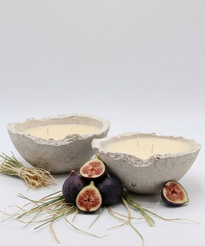 Two concrete bowls with candles and figs on a white background