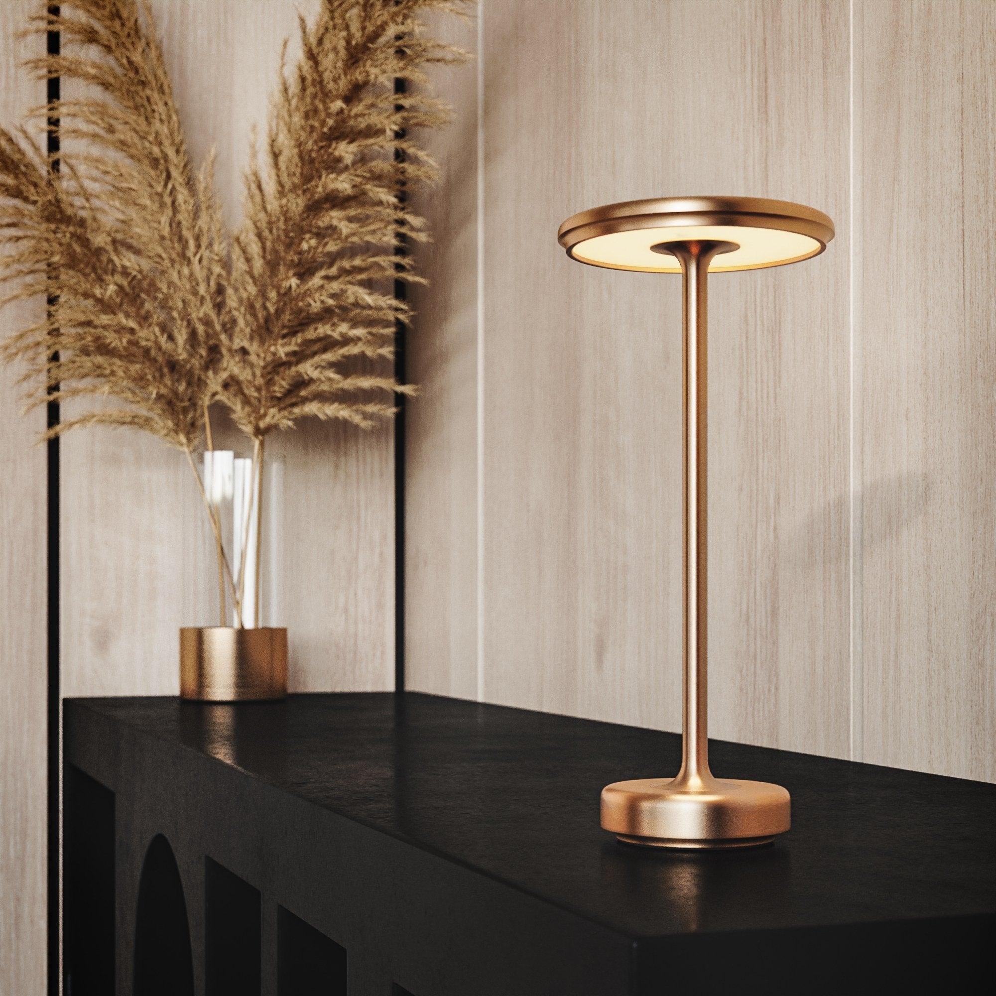 Gold cordless table lamp on a black console