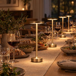 Several gold cordless lamps along a dinner party table